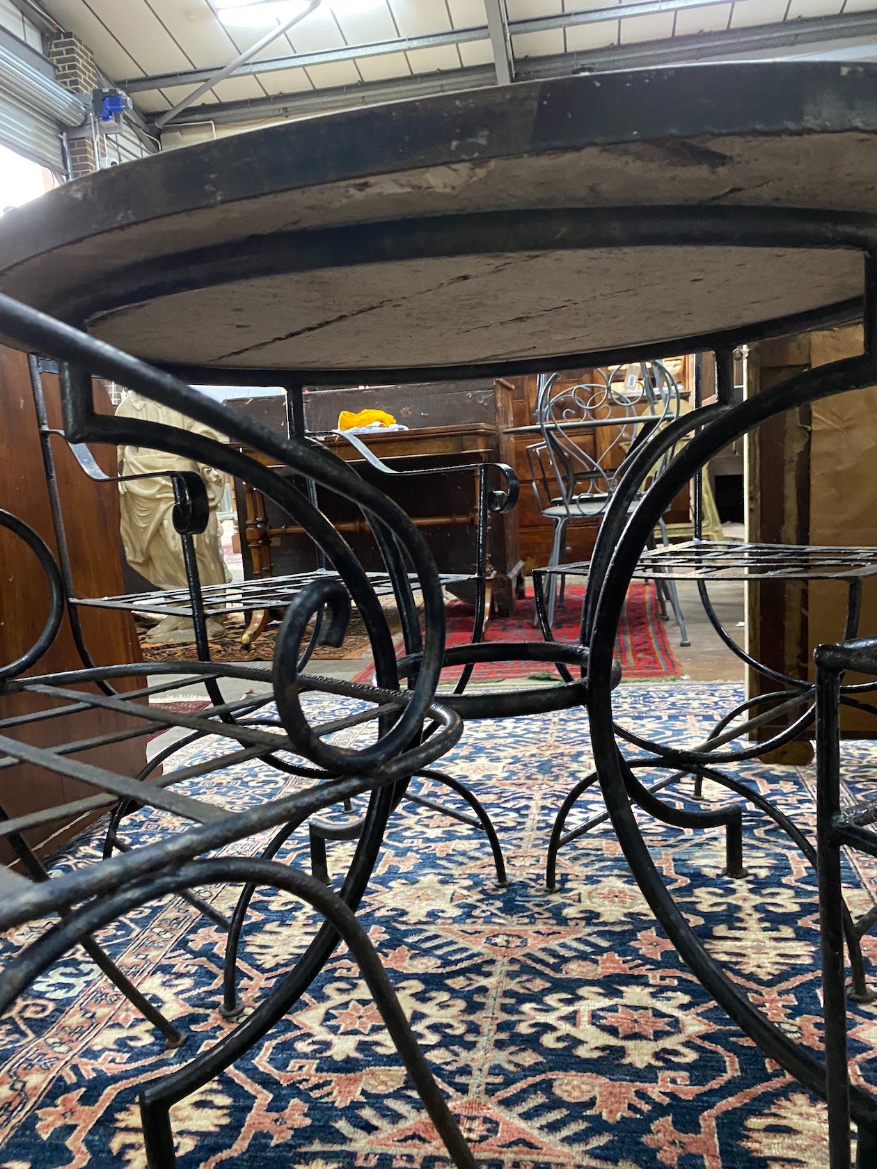 A circular mosaic top wrought iron garden table, diameter 100cm, height 74cm together with four wrought iron garden chairs, two with arms